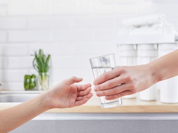 Persona porge un bicchiere d'acqua depurata ad un'altra persona